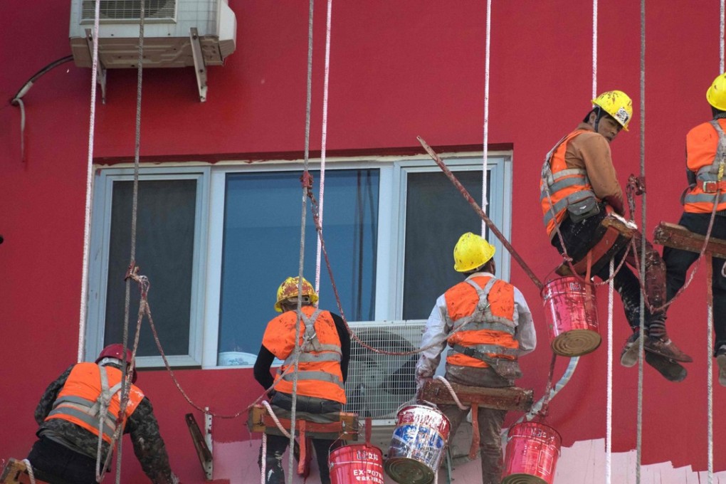 Chinese workers paint the outside of a residential building in Beijing. Photo: AFP