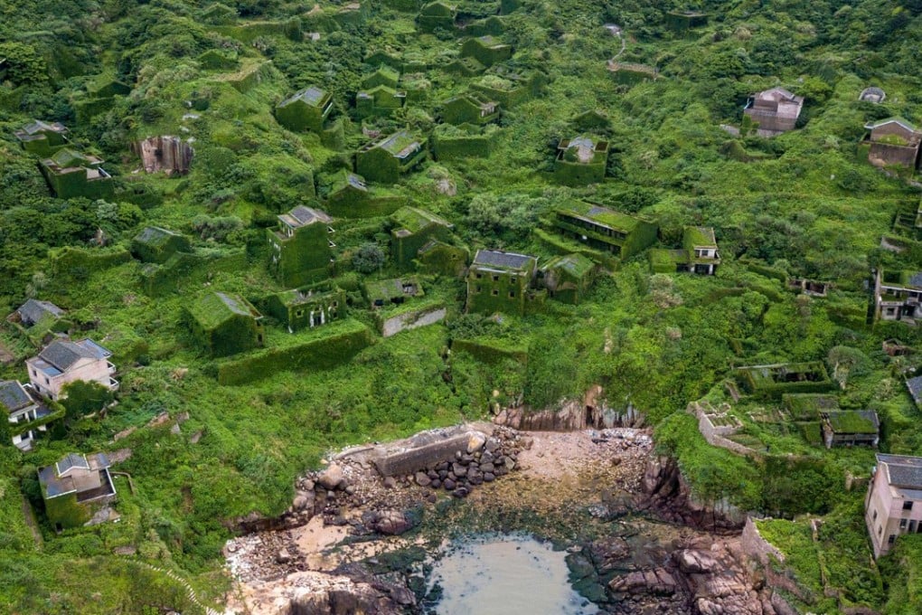 Abandoned houses in Houtouwan, these days covered by a layer of green. Photo: AFP