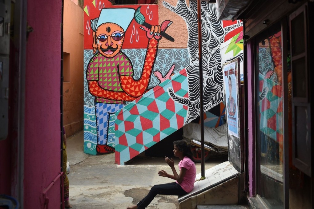 An Indian girl sits near a mural in Mumbai. Mumbai’s slums are getting a colourful makeover thanks to an organisation that aims to change how people perceive deprived areas in India’s financial capital. Photo: AFP