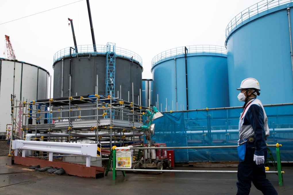 A TEPCO employee walks past storage tanks for contaminated water at the company's Fukushima Dai-ichi nuclear power plant in Okuma. The company said it was considering dismantling four reactors at the Fukushima Dai-ni, or No. 2, plant, which has not been restarted since the 2011 disaster. Photo: Reuters