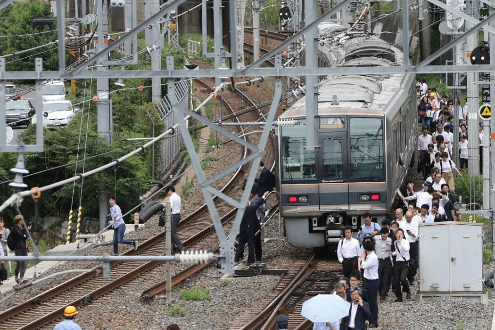 Train passengers were forced to walk along the tracks following an earthquake in Osaka on Monday morning. Photo: AFP