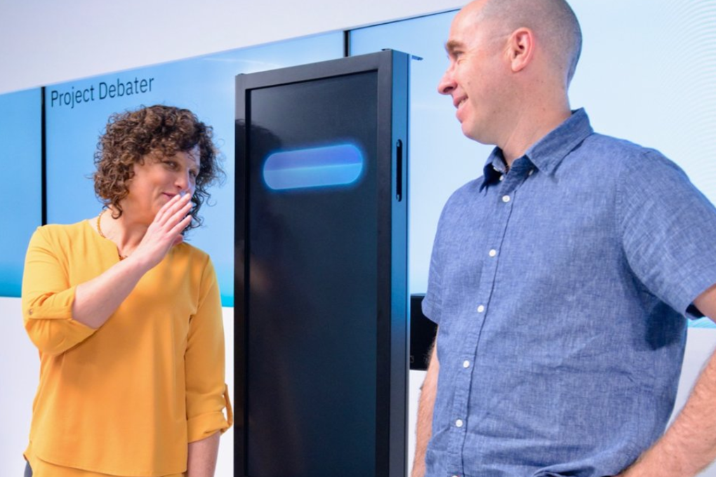 Dr. Ranit Aharonov (left) pretends to whisper to Project Debater, an AI system from IBM that is capable of debating humans. She and Dr. Noam Slonim are two of the scientists involved in developing Project Debater. Photo: Greg Sandoval/Business Insider
