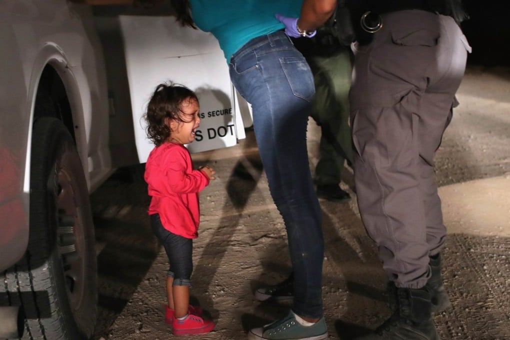 A two-year-old Honduran asylum seeker cries as her mother is searched and detained near the US-Mexico border, in McAllen, Texas. Photo: AFP