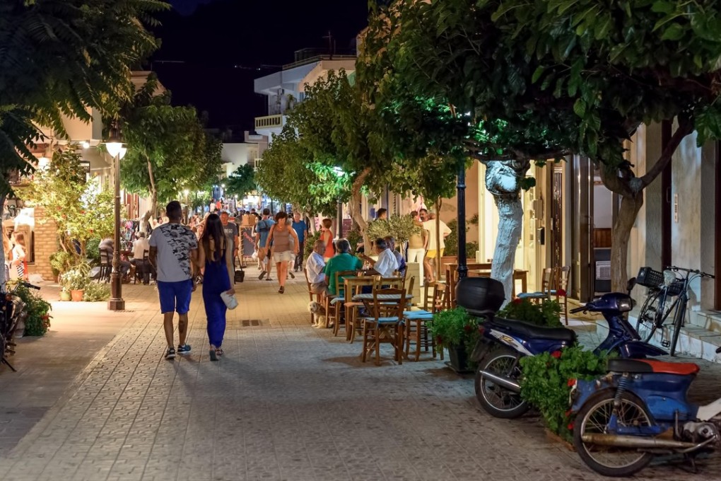 People stroll past al fresco diners in the town of Paleochora on Crete. Photo: Alamy
