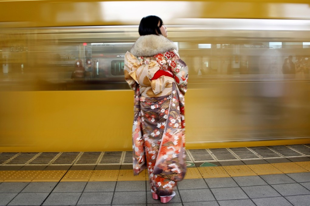 A woman waits for her train after attending a Coming of Age Day ceremony in Tokyo. Japan’s central bank maintained its loose monetary policy on Friday and downgraded its view on inflation, signalling that it will lag well behind its US and European peers in rolling back crisis-era stimulus. Photo: Reuters