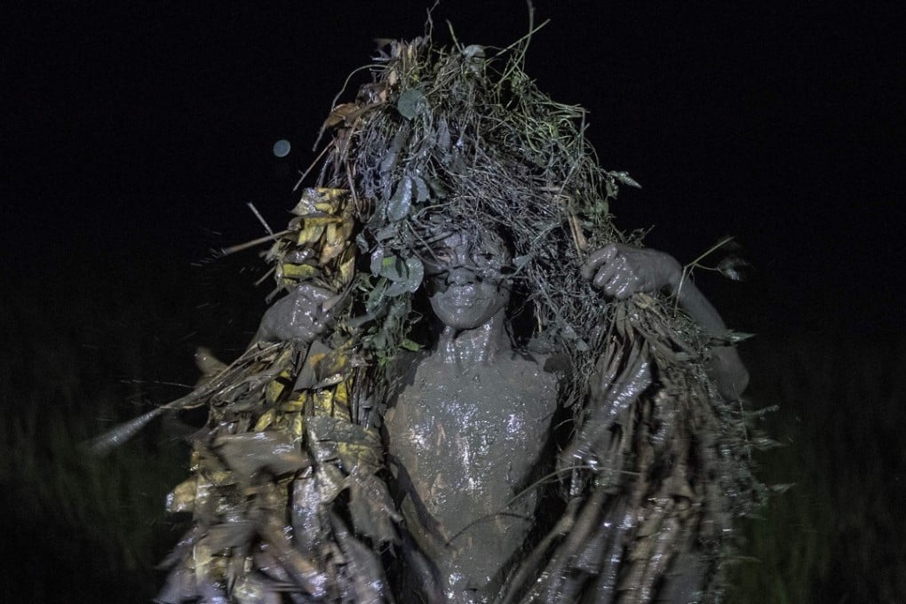 A mud-covered devotee wears a costume made of banana leaves. Photo: AFP