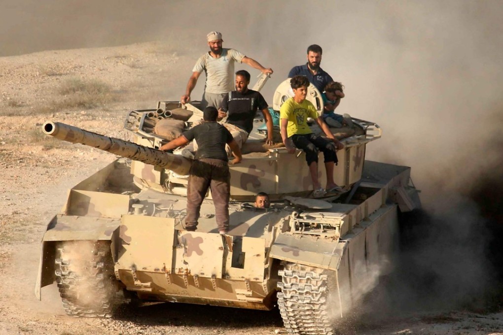 Syrian rebel fighters ride a tank in Daraa, southwestern Syria. Photo: AFP