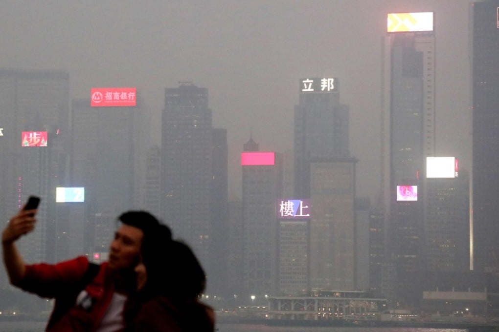 In this photo from January 2018, people pose at Tsim Sha Tsui with Hong Kong’s Victoria Harbour under heavy smog in the background. According to Bank of America Merrill Lynch, capital expenditure in Asia directed at climate change mitigation will need to increase to US$500 billion by 2030, from US$275 billion this year. Photo: K Y Cheng