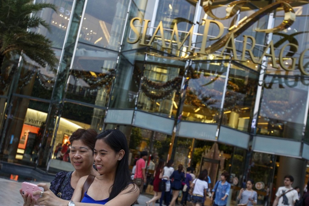 Tourists take a photo of themselves in front of Siam Paragon Department Store in central Bangkok. Photo: Reuters