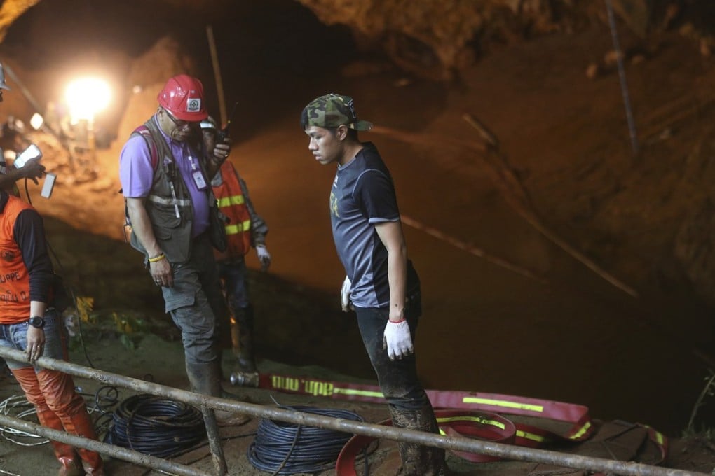 Rescue personnel walk out of the entrance to a cave complex where it's believed that 12 soccer team members and their coach went missing in Mae Sai, Chiang Rai province. Photo: AP