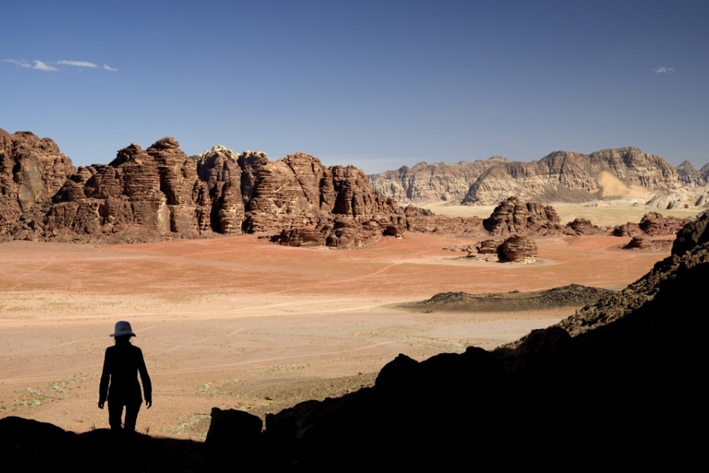 Steep cliffs tower over the red sand desert of Wadi Rum, a sandstone valley in southern Jordan. Photo: Photononstop