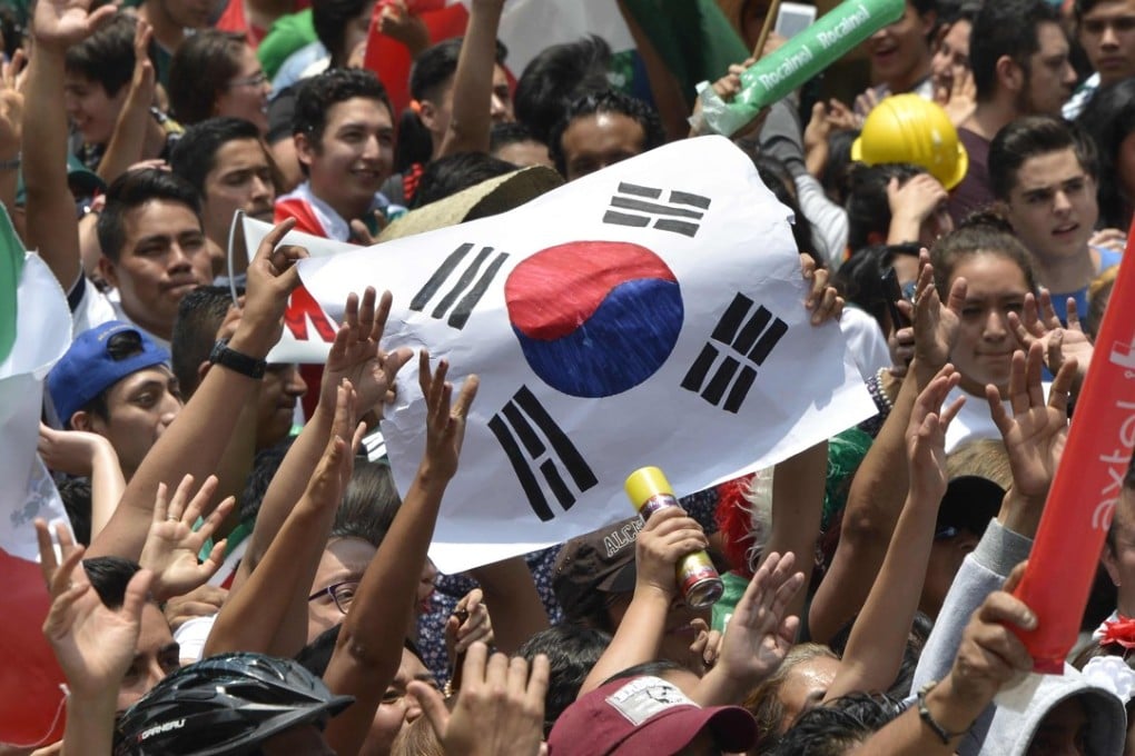 A football fan holds a flag of South Korea as thousands watch the World Cup match between Mexico and Sweden on a screen at the Angel de la Independencia Monument in Mexico City. Photo: AFP