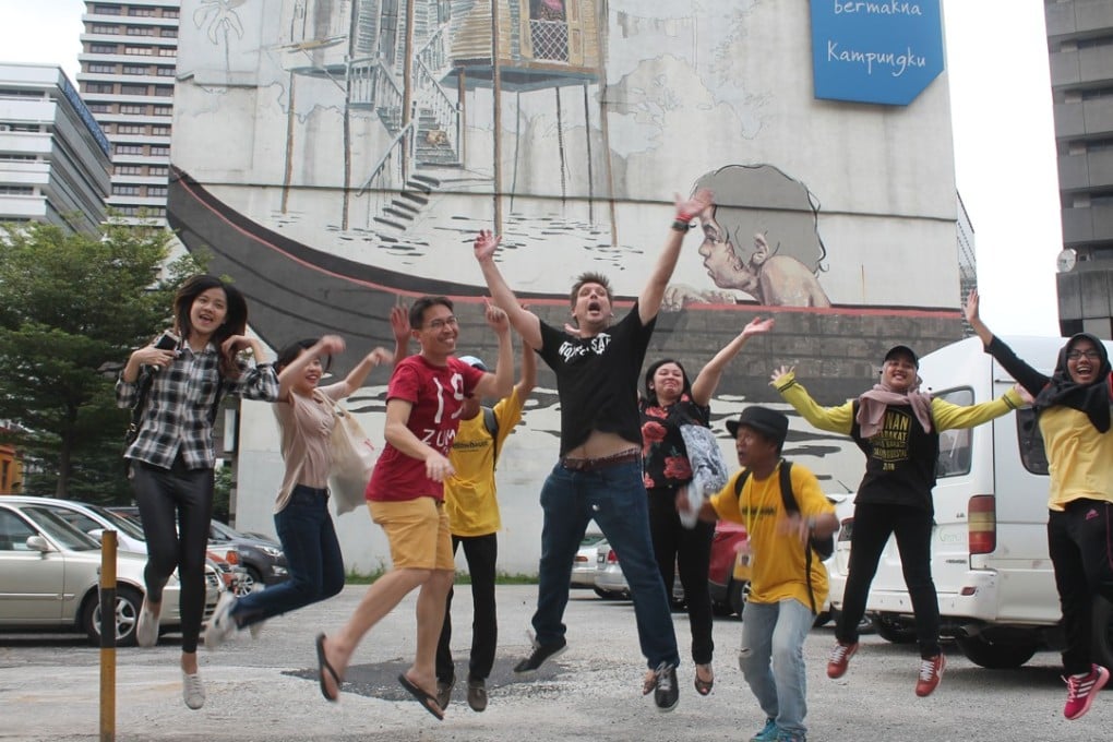 Tour participants jump in front of a mural after being shown around Kuala Lumput by a Yellow House KL guide. Photo: TK Letchumy