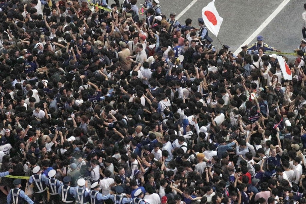 Police try to control Japanese soccer fans celebrating their victory over Colombia in the World Cup. Photo: Reuters
