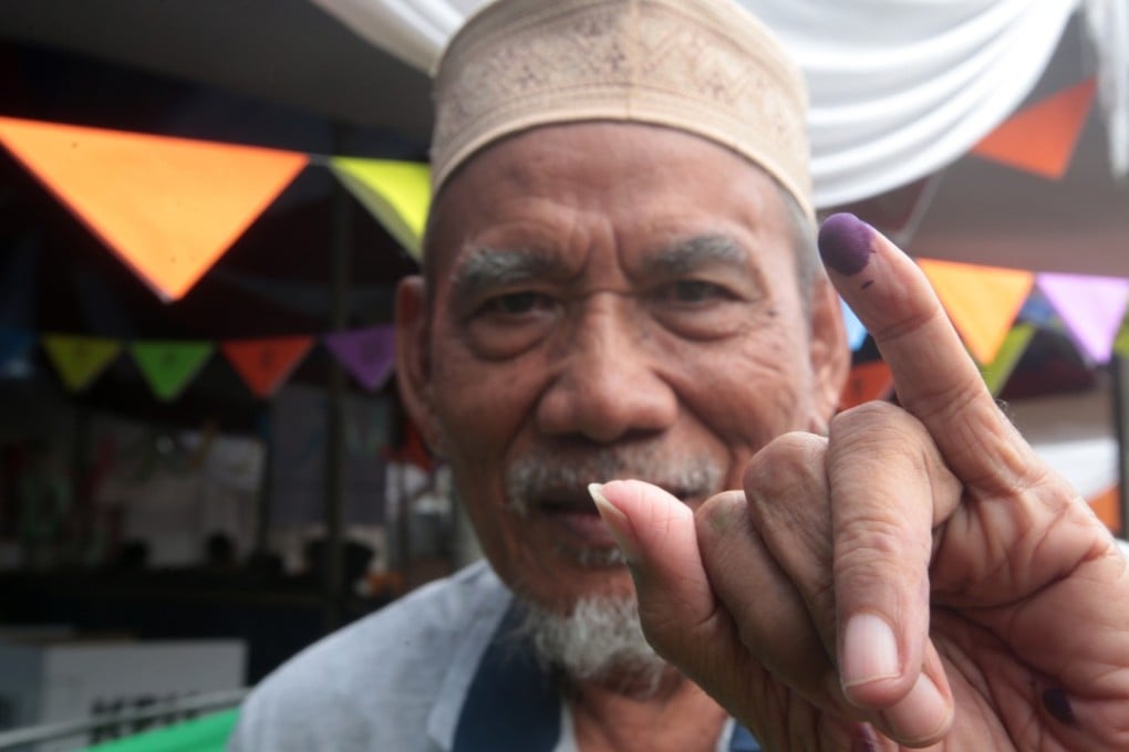 An Indonesian man shows his finger after voting at a polling station in Depok, Indonesia. Photo: EPA