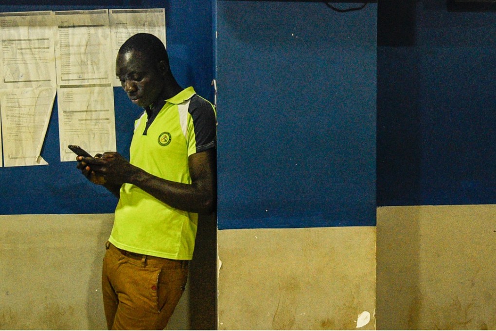 A Ugandan man looking at his mobile phone in a shop in Kampala. Photo: AFP