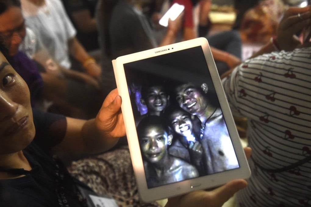 A family member shows the latest pictures of the missing boys taken by rescue divers inside Tham Luang cave when all members of the youth football team and their coach were found alive. Photo: AFP