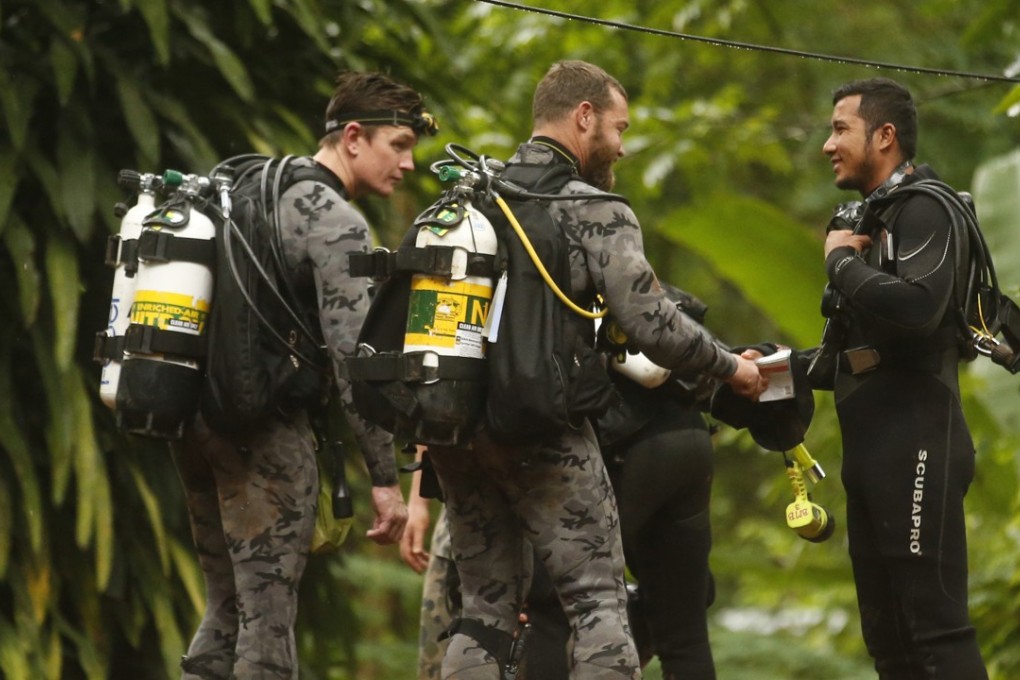 Australian and Thai rescue divers coordinate at the entrance to the cave where 12 boys and their soccer coach are trapped in Chiang Rai province, in northern Thailand, on Tuesday. Photo: AP