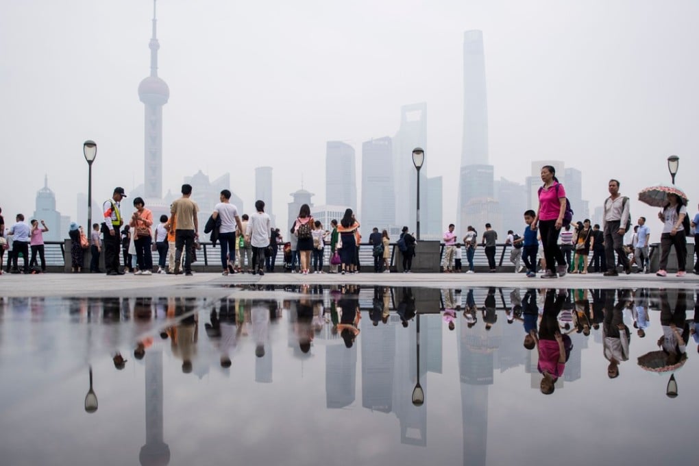 Tourists flock to the promenade on the Bund along the Huangpu River, seen against the skyline of the Lujiazui Financial District in Shanghai on a hazy day on May 29. The value of China’s currency has dropped sharply in the past two weeks, with some speculating that the fall was a gambit in the ongoing trade war with the US, but the People’s Bank of China announced it would defend the currency on July 3. Photo: AFP