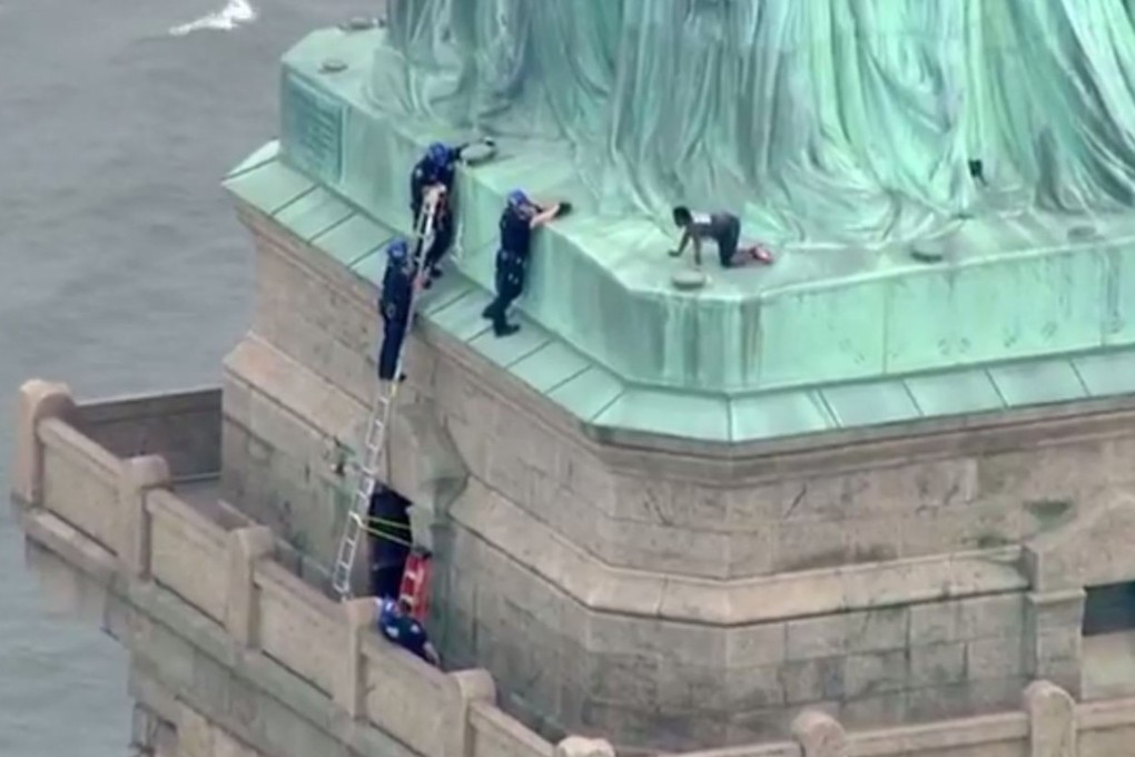 This still image taken from video Courtesy of PIX11 News in New York, shows police talking to a woman (right) who climbed to the base of the Statue of Liberty in New York on July 4. Photo: Agence France-Presse