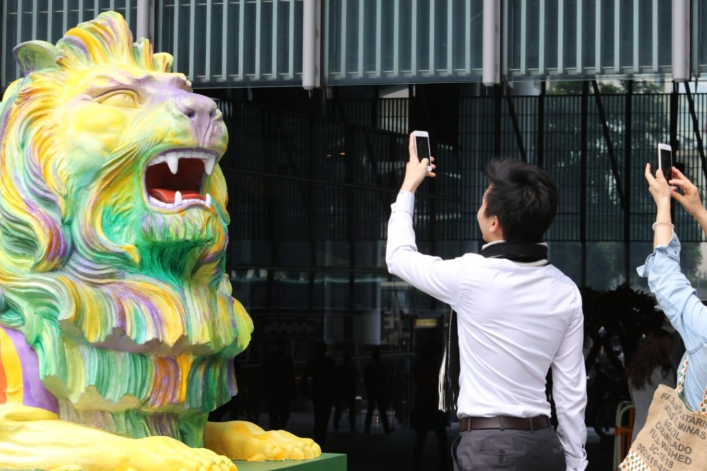 Passers-by take photos of the iconic HSBC lions given a colourful makeover in support of the rights of sexual minorities, in Central in December 2016. Photo: Felix Wong