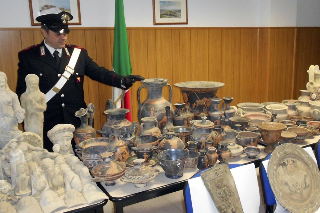 An Italian officer looks at Greek and Roman objects recovered on Wednesday after police dismantled an international ring trafficking ancient artefacts. Photo: Carabinieri Police via AP
