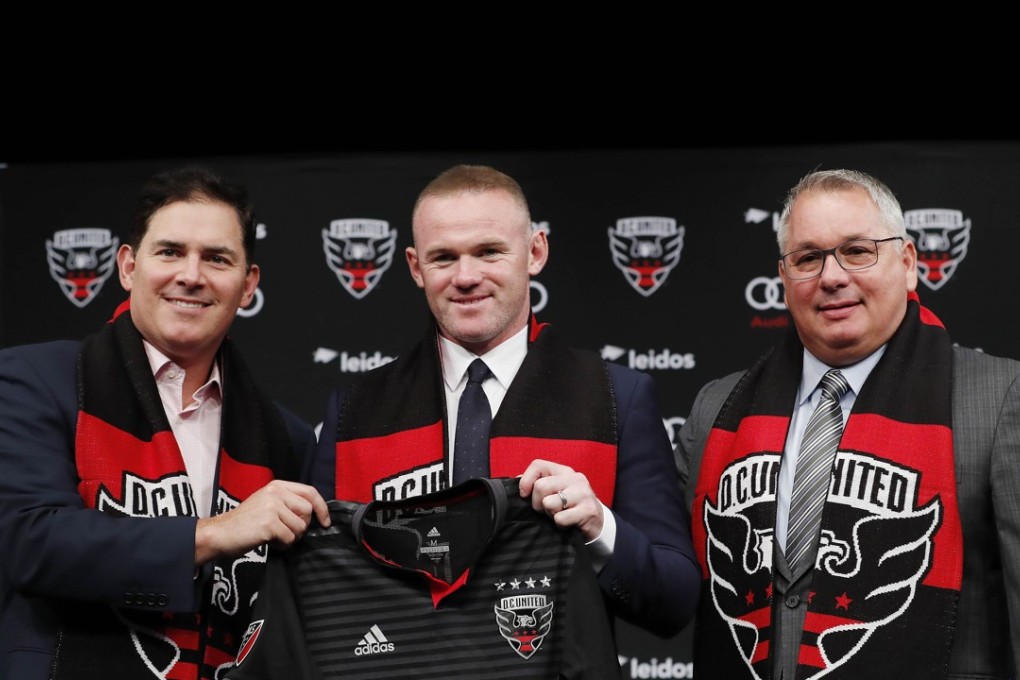 DC United Managing Partner and CEO Jason Levien, Wayne Rooney, and DC United General Manager Dave Kasper pose with a jersey. Photo: AFP