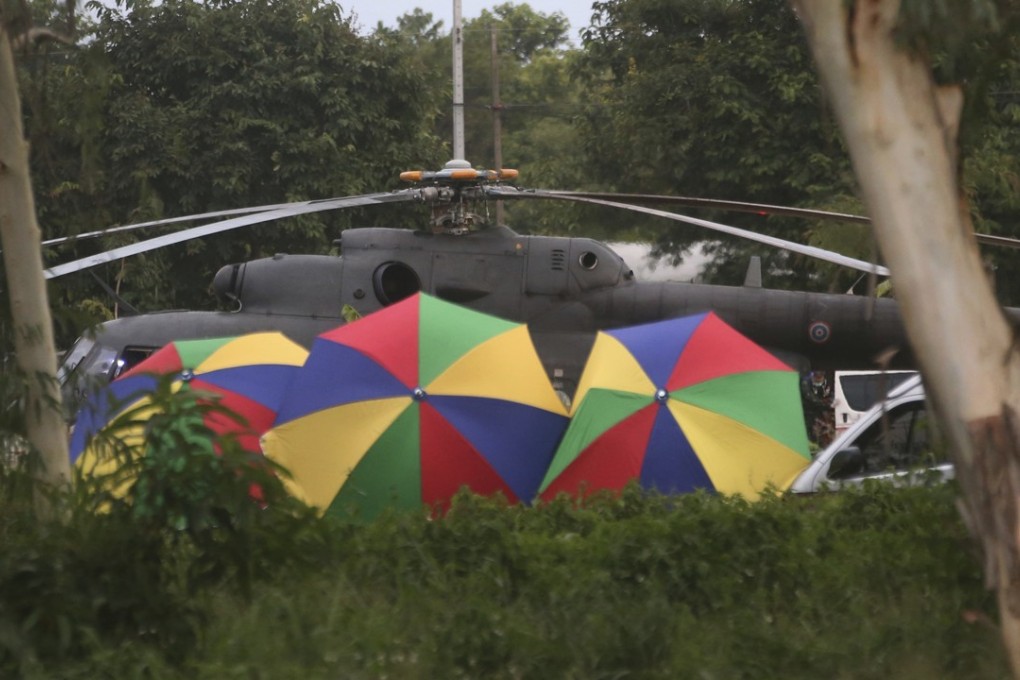 Local police place umbrellas around an evacuation helicopter near the cave in Mae Sai, Chiang Rai. Photo: AP