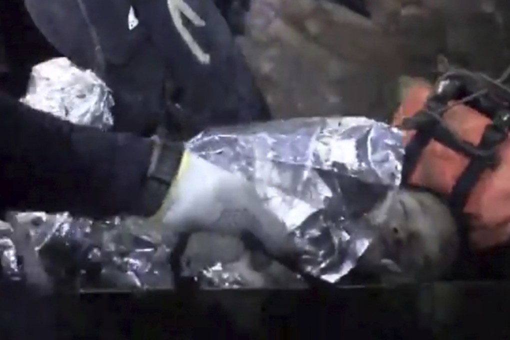 An image captured from a video inside the cave shows a boy with his eyes closed but appears conscious, with people gathered around him. Photo: AP