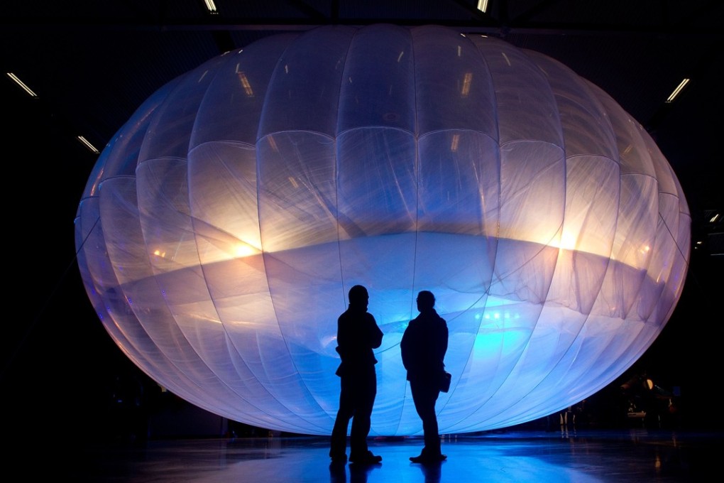 Visitors stand next to an early Google Project Loon balloon. Photo: Handout