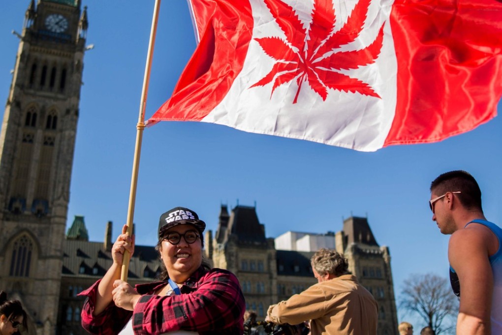 A woman waves a flag with a marijuana leef on it next to a group gathered to celebrate National Marijuana Day on Parliament Hill in Ottawa in 2016. Using and selling cannabis will be legal in Canada from October 17. Photo: AFP