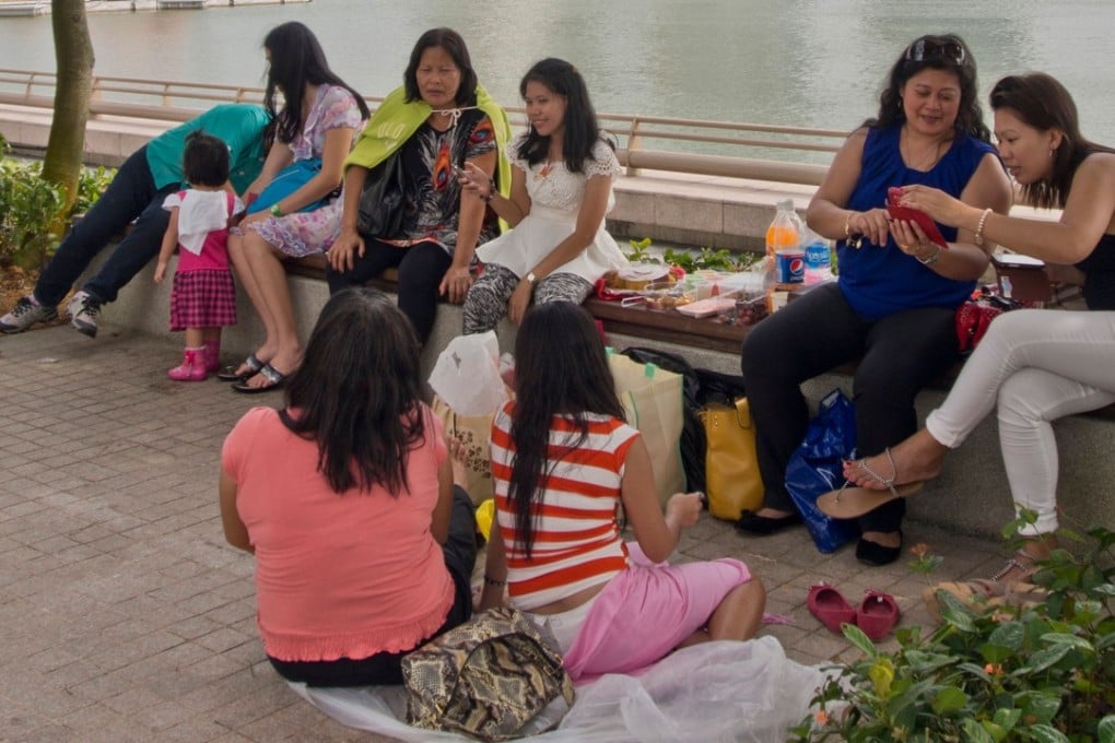 Migrant domestic workers enjoy a day off at Marina Bay in downtown Singapore. Photo: Alamy