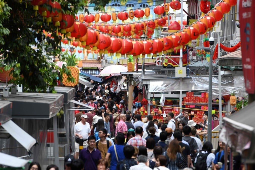 People along a crowded alleyway past stalls selling gifts and decorative items in Chinatown in Singapore on February 19, 2018. Photo: AFP