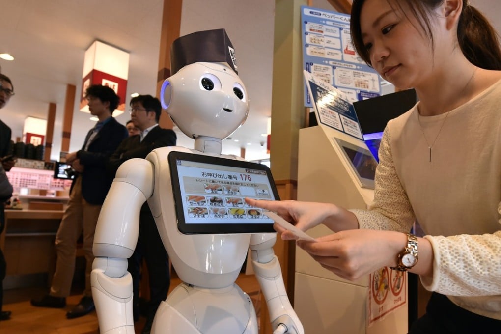 An employee at a sushi restaurant looks at a touch screen set up on a humanoid robot, in Saitama, Japan. The ability of robots to handle services like receiving and helping customers to their tables could have an impact on jobs in the restaurant sector. Photo: AFP