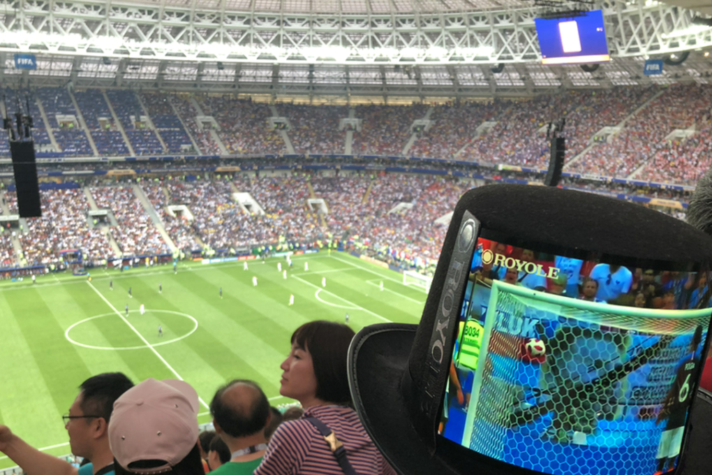 A spectator watching the football 2018 World Cup in Russia, wearing a top hat with a flexible display from Royole.