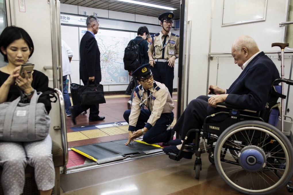 Subway employees help an elderly man in a wheelchair to disembark from the train at a station in Tokyo. Photo: AFP