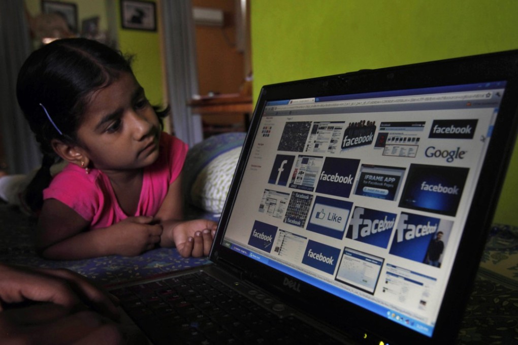 An Indian works on a laptop as a child watches in Hyderabad, India. Photo: AP