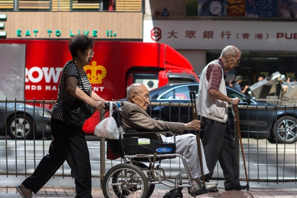 A woman pushes an elderly man in a wheelchair in Central district, Hong Kong. Photo: EPA