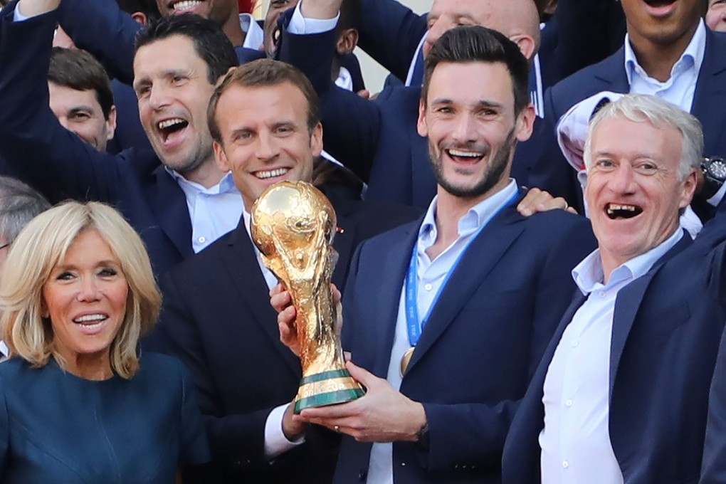 France goalkeeper Hugo Lloris (centre) holds the trophy next to coach Didier Deschamps (right) as French President Emmanuel Macron and his wife Brigitte Macron welcome players and staff members after they won the World Cup final. Photo: AFP