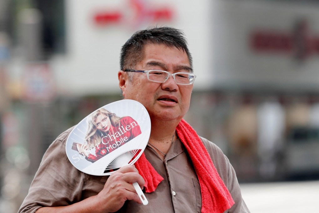 A man uses a fan as he walks on a street in Tokyo. File photo: Reuters