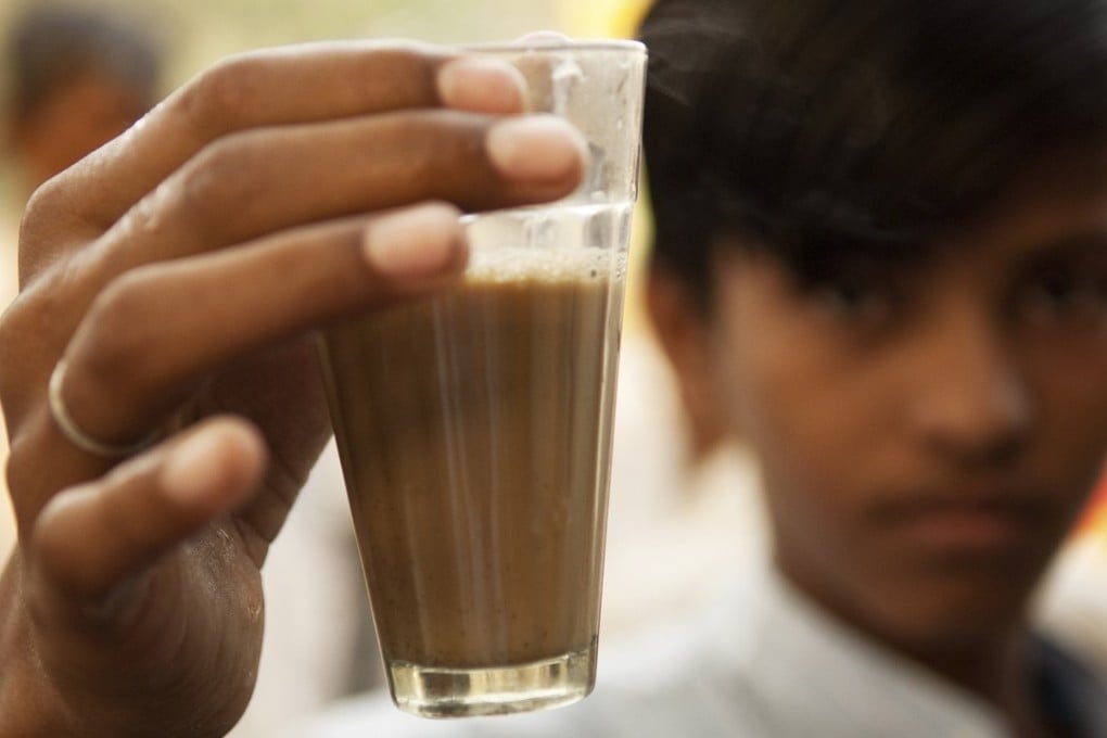 A boy holds up a cup of tea in India. Photo: Alamy