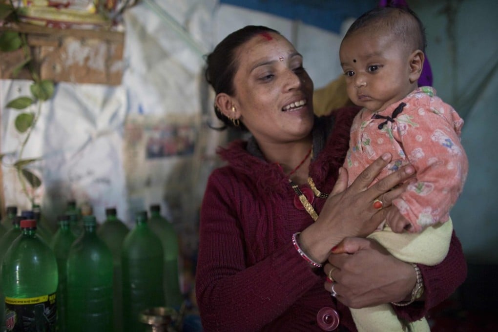 Meera Nepali plays with her son at her home in the Ramechhap district in Nepal. She benefited from a programme that paid her bus fares to and from hospital and which has helped more than two million Nepali women access medical services. Photo: AFP
