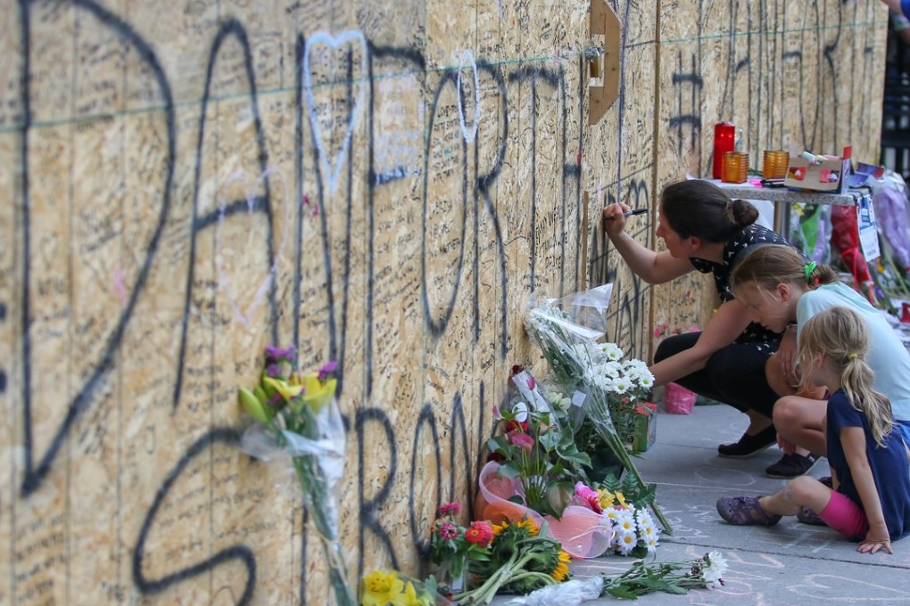 People write messages on construction boarding after a mass shooting on Danforth Avenue in Toronto. Photo: Reuters