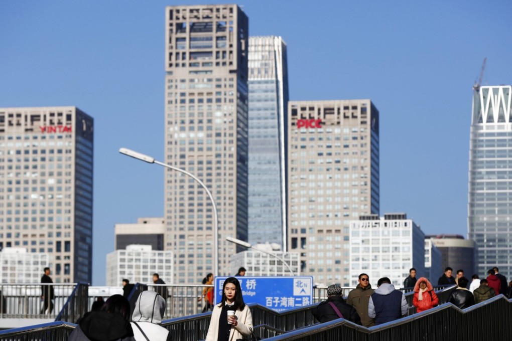 People walk on an overpass in Beijing, with the skyline of the Chinese capital’s Central Business District in the background. China’s 1.3 trillion yuan peer-to-peer lending market is undergoing a massive shakeout, with hundreds of lenders collapsing or exiting the business over the past two months, leaving consumers from all walks of life unable to withdraw their money. Photo: EPA