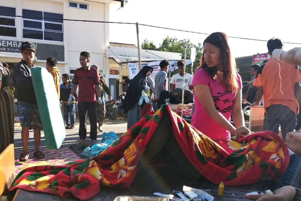 A woman stands near an injured person outside a hospital after an earthquake hit Sembalun Selong village in Lombok. Photo: Reuters