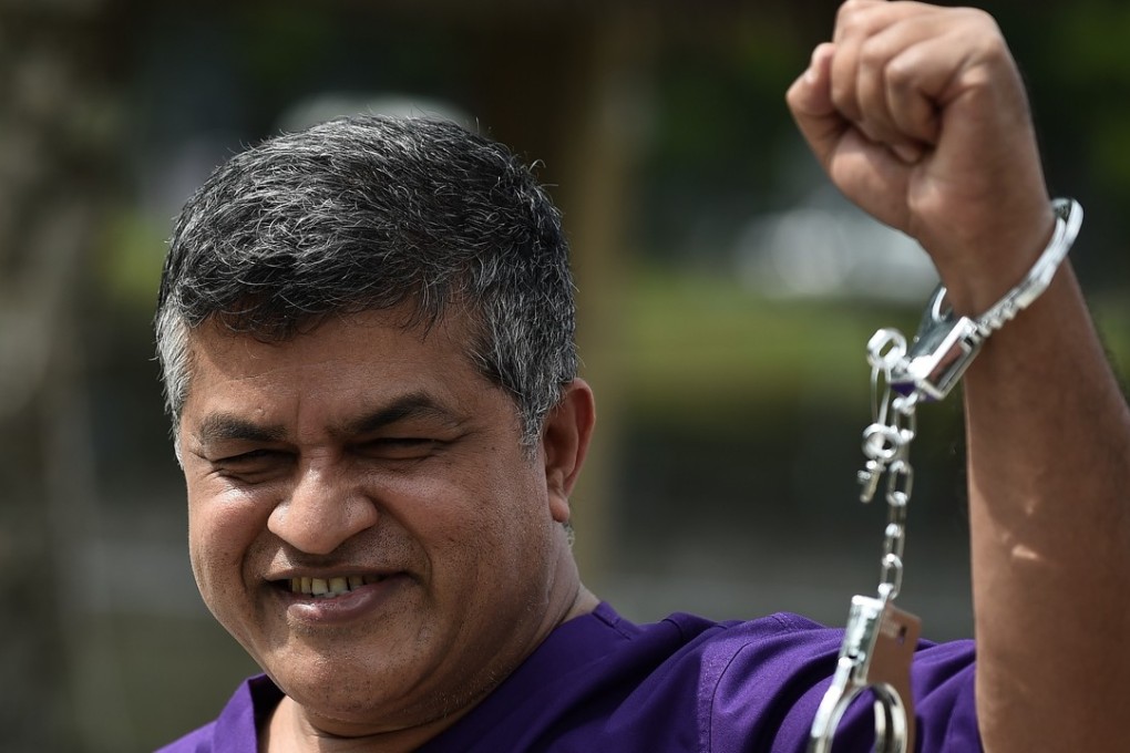 Malaysian political cartoonist Zulkiflee Anwar Haque, or Zunar, reacts with mock handcuffs during his case at Duta Court, in Kuala Lumpur, in April 2015. Photo: AFP