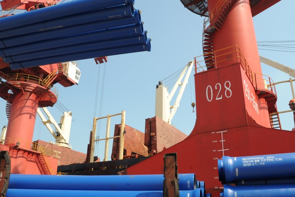 A worker looks on as a crane lifts steel pipes for export at a port in Lianyungang, China on July 15. China’s steel and aluminium exports have been among the first targets for tariffs by the Trump administration. Photo: Reuters