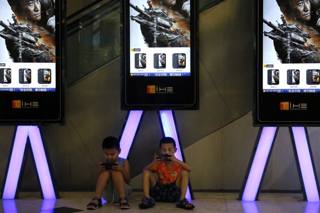 Children play with their smartphones while waiting to watch a film, at a cinema in Beijing in August 2017. Photo: AP