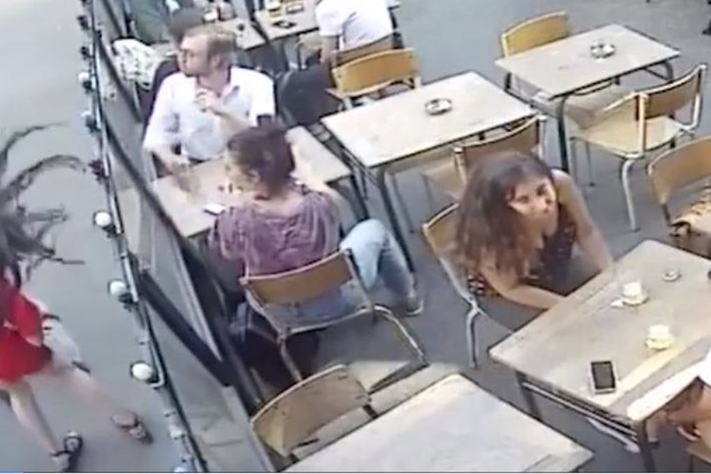 Marie Laguerre's hair goes flying as her head is snapped back by a blow from her attacker, outside a cafe in Paris on Tuesday July 24. Photo: YouTube