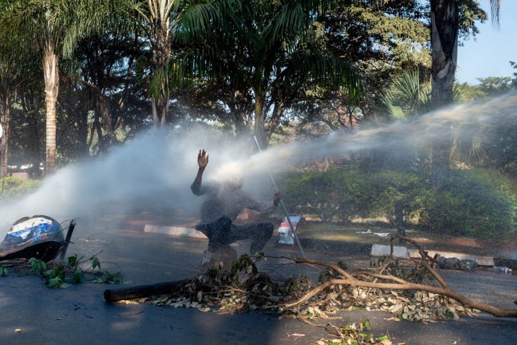 A protester was hit in the face by a water cannon outside the gates of the Zimbabwe Electoral Commission during a protest against election results in Harare, Zimbabwe, on Wednesday. Photo: EPA-EFE